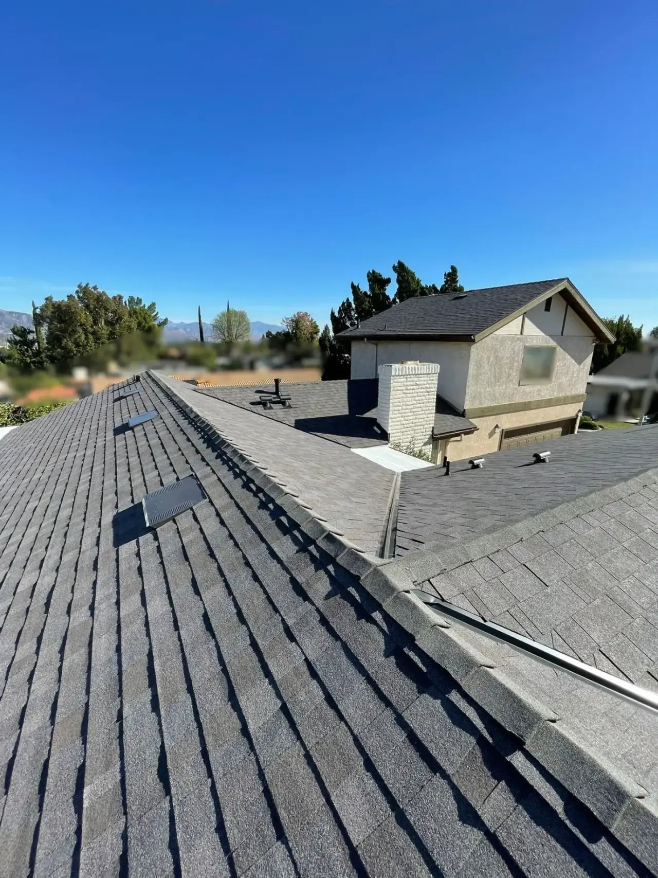 Hillside home with a new shingle roof under clear skies